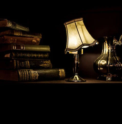 An old desk lamp illuminating legal books on a dark shelf, evoking a traditional law library setting.